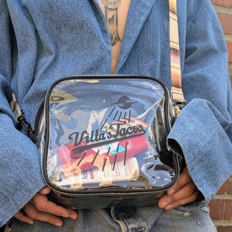 Villas Tacos Essential Bag clear crossbody worn with adjustable strap, featuring logo and carrying everyday essentials in LA streetwear style